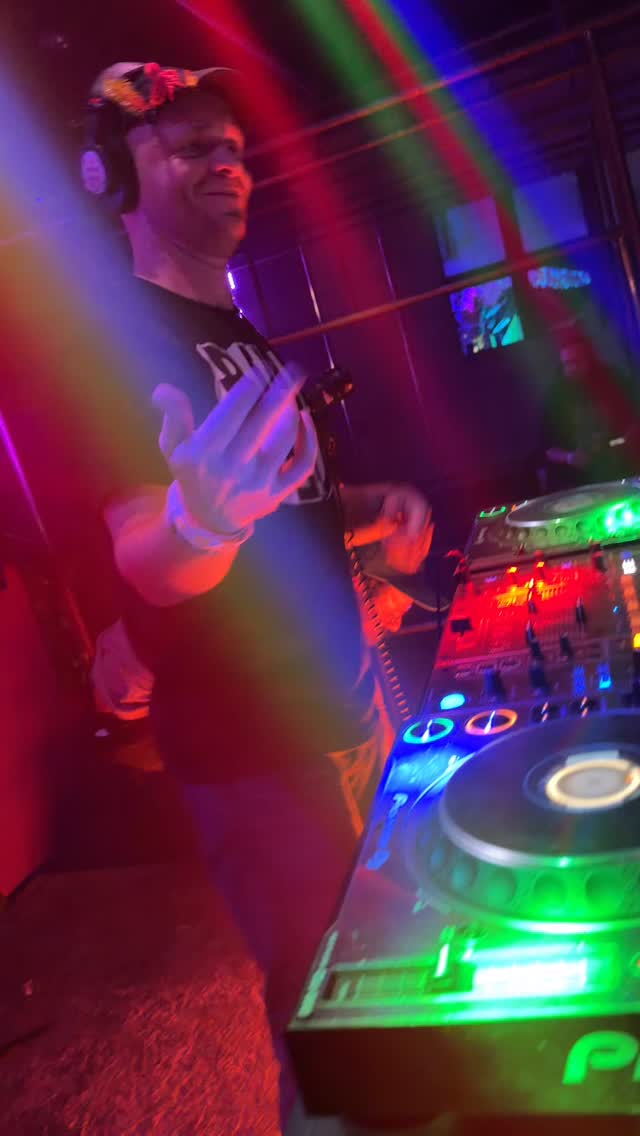 Bill Plur mid-set at the CDJs under red and green lights